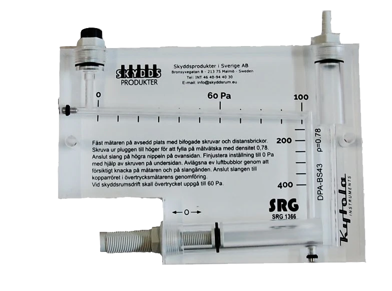 En transparent manometer med mätskalor, två vertikala rör, märkta markeringar och tryckta instruktioner på svenska och engelska, används för att mäta tryckskillnad i pascal.